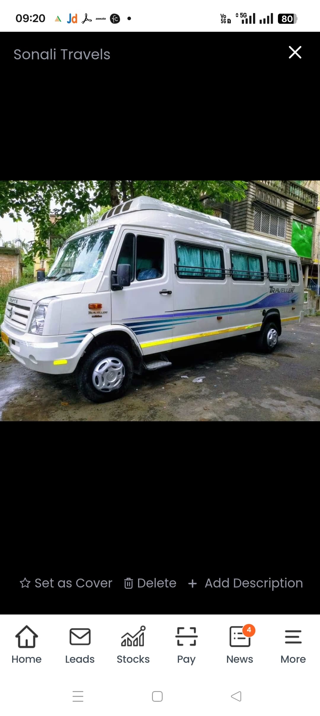 नीले ग्राफिक्स और चैती पर्दों वाली सफेद फोर्स ट्रैवलर मिनीबस बाहर सड़क पर खड़ी है।
